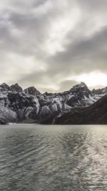 Gokyo Gölü ve karlı dağlar. Dramatik gökyüzü ve kayan güneş. Himalaya, Nepal. Dikey Video
