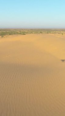 Drone çöldeki kum tepelerinin üzerinde sorunsuzca uçuyor. Hava görüntüsü. Dikey Video
