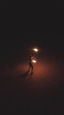 Kaslı beyaz adam numaralarıyla ateş gösterisi yapıyor. Hava görüntüsü. Dikey Video