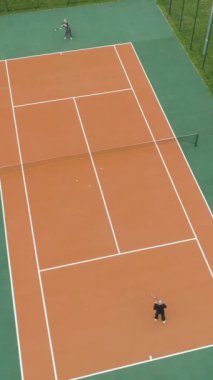 Yaşlı insanlar yeşil parktaki kortta tenis oynuyorlar. Hava görüntüsü. Dikey Video