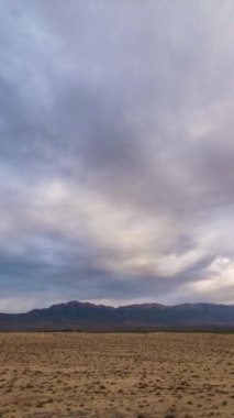 Arkaplanda Tepeler ve Çölde Renkli Bulutların Zaman Hızı. Dikey Video