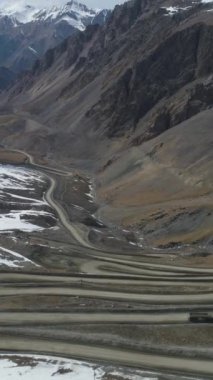 Kamyon Yüksek Dağlarda Yol Geçidine Gidiyor. Havadan Yukarıdan Aşağı Görünümü. Drone ileri uçuyor, Kamera aşağı eğiliyor. Atış ayarlanıyor. Dikey Video