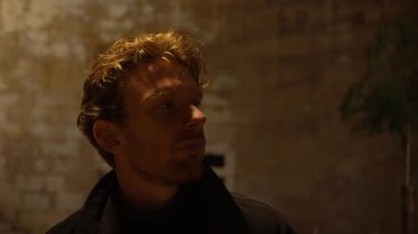 Güler yüzlü, İskandinav, koyu sarı saçlı, gece vakti Avrupa 'da siyah paltolu bir adam. Lizbon Eski Kasabası, Portekiz. Yakın çekim.