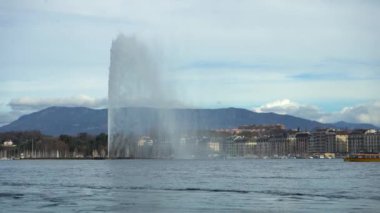 Bulutlu bir günde Cenevre Su Fıskiyesi ve feribot geçiyor. İsviçre.