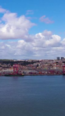 Lisbon Skyline ve Tagus Nehri. Mavi Gök ve Kümülüs Bulutları. Portekiz. Hava görüntüsü. İnsansız hava aracı yandan uçuyor. Dikey Video
