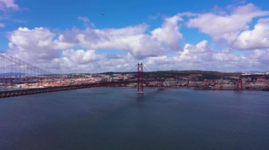Ponte 25 de Abril Askı Köprüsü ve Lisbon Skyline. 25 Nisan Köprüsü. Mavi Gök ve Kümülüs Pofuduk Bulutları. Portekiz. Hava görüntüsü. İnsansız Hava Aracı Yukarı ve Geri Uçar