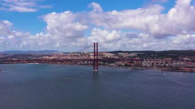 Ponte 25 de Abril Askı Köprüsü ve Lisbon Skyline. 25 Nisan Köprüsü. Mavi Gök ve Kümülüs Pofuduk Bulutları. Portekiz. Hava görüntüsü. Drone ileri ve yukarı doğru uçuyor. Orta Çekim
