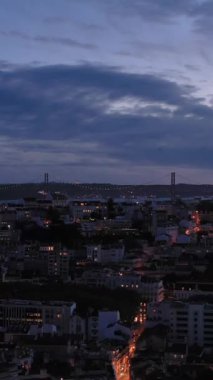 Lisbon Skyline, Tagus Nehri ve 25 Nisan Köprüsü Akşam Alacakaranlığı 'nda. Mavi Saat. Portekiz. Hava görüntüsü. Drone yukarı doğru uçuyor. Dikey Video