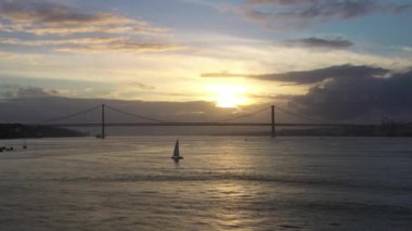 Sunset ve Yelkenli Yat 'ta 25 Nisan Askı Köprüsü. Ponte 25 de Abril ve Tagus Nehri. Portekiz. Hava görüntüsü. Altın Saat. Yörüngede. Orta Çekim