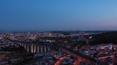Lisbon Skyline, Aguas Livres Aqueduct ve 25 Nisan Köprüsü 'nü Akşam Alacakaranlığı' nda aydınlattı. Mavi Saat. Portekiz. Hava görüntüsü. Yörüngede