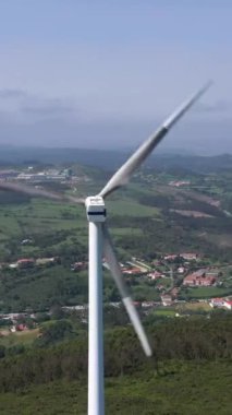 Güneşli bir günde Portekiz 'in Yeşil Kırsal Bölgesinde Bıçaklı Rüzgar Türbini. Hava görüntüsü. Alternatif Yenilenebilir Enerji. Yörüngede. Dikey Video