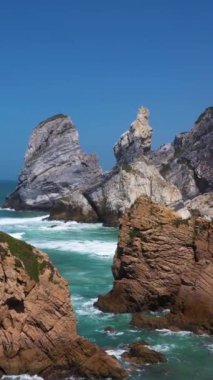 Ursa Sahili, İki Deniz Yığını, Kayalıklar ve Güneşli Gün 'de Atlantik Okyanusu Dalgaları. Portekiz. Hava görüntüsü. İnsansız hava aracı uçurumlara doğru ilerliyor. Dikey Video