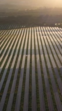 Portekiz 'in Sunset kentindeki Büyük Fotovoltaik Güneş Panelleri Alanı. Güneş ışığı yansıması. Hava görüntüsü. Drone ileri gidiyor. Dikey Video