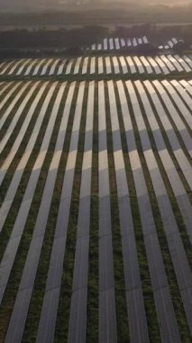Portekiz 'in Sunset kentindeki Büyük Fotovoltaik Güneş Panelleri Alanı. Güneş ışığı yansıması. Hava görüntüsü. İnsansız hava aracı yan yana hareket ediyor. Dikey Video