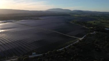 ALENQUER, PORTUGAL - 15 Nisan 2024: Portekiz 'de Sunset' teki Büyük Fotovoltaik Güneş Panelleri Alanı. Güneş ışığı yansıması. Hava görüntüsü. İnsansız hava aracı ileri, yana doğru hareket ediyor. Görüntü Görüntüsü