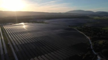 ALENQUER, PORTUGAL - 15 Nisan 2024: Portekiz 'in Sunset kentindeki Dev Fotovoltaik Güneş Panelleri İstasyonu. Güneş ışığı yansıması. Hava görüntüsü. Drone Geriye Gidiyor