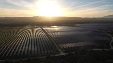 ALENQUER, PORTUGAL - 15 Nisan 2024: Portekiz 'in Sunset kentindeki Dev Fotovoltaik Güneş Panelleri İstasyonu. Güneş ışığı yansıması. Hava görüntüsü. Drone Geriye Gidiyor