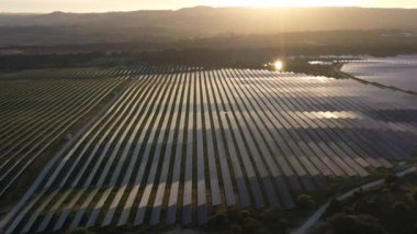 ALENQUER, PORTUGAL - 15 Nisan 2024: Portekiz 'in Sunset kentindeki Dev Fotovoltaik Güneş Panelleri İstasyonu. Güneş ışığı yansıması. Hava görüntüsü. Yörüngede
