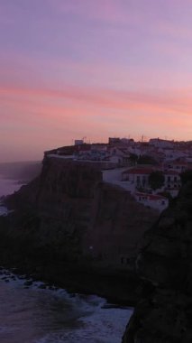 Azenhas, Sabah Alacakaranlığı, Atlantik Okyanusu 'nun Kayalıkları ve Dalgaları' nda Portekiz 'deki Mar Village' ı yapıyor. Hava görüntüsü. Drone ileri ve yukarı hareket ediyor. Pembe Gök. Atış ayarlanıyor. Dikey Video