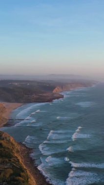 Ericeira yakınlarında Portekiz kıyısı. Atlantik Okyanusu 'nun Kayalıkları, Sahilleri ve Dalgaları. Hava görüntüsü. Drone ileri gidiyor. Dikey Video