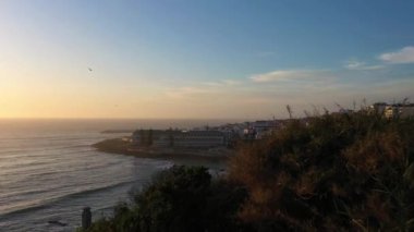 ERICEIRA, PORTUGAL - 16 Nisan 2024: Günbatımı, Atlantik Okyanusu ve Sahildeki Ericeira City. Portekiz. Hava görüntüsü. Drone ileri ve yukarı hareket ediyor. Çekim Kuruluyor
