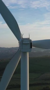 Günbatımında Portekiz 'in Yeşil Kırsal Bölgesinde Rüzgar Türbinleri. Hava görüntüsü. Alternatif Yenilenebilir Enerji. Drone geriye doğru hareket ediyor. Dikey Video