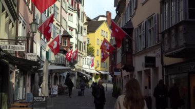 ZURİH, SWitzERLAND - 25 Nisan 2024: İsviçre Dalgalanan Bayraklar ve Eski Kasabadaki İnsanlar.