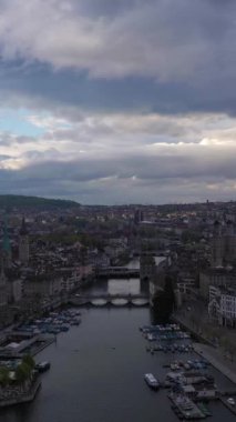 Bulutlu Gece 'deki Zürih Eski Şehir ve Limmat Nehri. İsviçre. Hava görüntüsü. Drone ileri ve yukarı hareket ediyor. Dikey Video