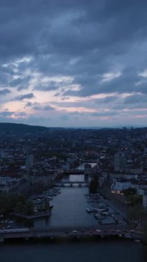 Akşam Alacakaranlığı 'nda Zürih Şehri Eski Şehir Skyline ve Limmat Nehri. İsviçre. Hava görüntüsü. Drone ileri gidiyor. Dikey Video