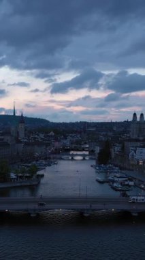 Akşam Alacakaranlığı 'nda Zürih Şehri Eski Şehir Skyline ve Limmat Nehri. Dramatik Bulutlar. İsviçre. Hava görüntüsü. Drone yukarı ve geri hareket ediyor. Dikey Video