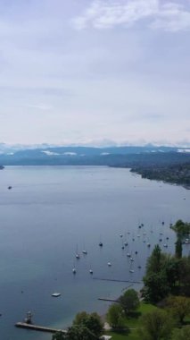 Güneşli bir günde Zürih Gölü ve İsviçre Alpleri. Karla kaplı dağlar. İsviçre. Hava görüntüsü. Drone ileri gidiyor. Dikey Video