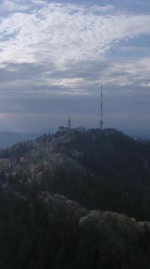 Bulutlu bir günde Uetliberg Dağı ve Radyo Kulesi. İsviçre. Hava görüntüsü. Drone ileri gidiyor. Dikey Video
