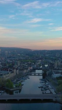 Zürih Şehir Merkezi Skyline ve Limmat Nehri Sunrise 'da. Altın Saat. İsviçre. Hava görüntüsü. İnsansız hava aracı yan yana hareket ediyor. Dikey Video