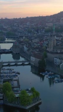 Zürih Şehir Merkezi ve Gündoğumunda Limmat Nehri. Altın Saat. İsviçre. Hava görüntüsü. Yörüngede. Dikey Video