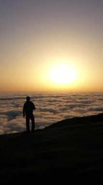 Sunrise 'daki Tepedeki Duran Adam' ın silueti. Bulut Dönüşümü. Hava Aracı Atışı. Madeira, Portekiz. İlerleme kaydediyoruz. Dikey Video