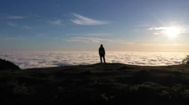 Güneşin doğuşunda Tepedeki Adam 'ın Silueti. Bulutlar Ters Dönüyor. Hava Aracı Atışı. Madeira, Portekiz. Yörüngede