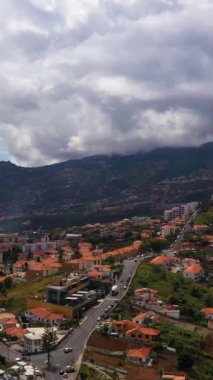 Bulutlu bir günde Funchal Şehri ve Dağları. Dramatik Gökyüzü. Madeira, Portekiz. Hava Aracı Atışı. İlerleme kaydediyoruz. Dikey Video