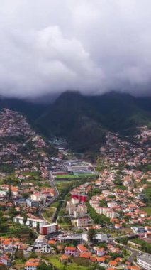 Bulutlu bir günde Funchal City ve Hills. Kara Fırtınalı Gökyüzü. Madeira, Portekiz. Hava Aracı Atışı. Yanlamasına hareket ediyor. Dikey Video