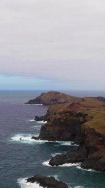 Bulutlu bir günde Madeira Adası 'nın en doğu noktasında. Kayalıklar ve Okyanus. Portekiz. Hava Aracı Atışı. İlerleme kaydediyoruz. Dikey Video