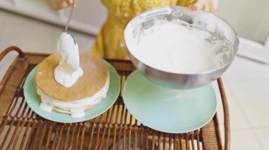 Pastanın üstüne kaşık sürerek krem şanti serpiştiren kadın. Yüksek açılı atış. Yavaş Hareket