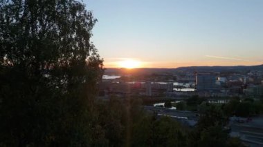 Oslo Şehir Merkezi, Norveç Yazın Sunset 'te. Hava Aracı Atışı. Ağaçlar arasında yavaşça ilerliyorum. Açılış Çekimi Kuruluyor