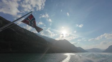 Güneşli bir günde Jotunheimen Ulusal Parkı 'nda Norveç Bayrağı sallamak. Mavi Gök ve Dağlar. Ferry Stern 'den yan görüntü. Yavaş Hareket