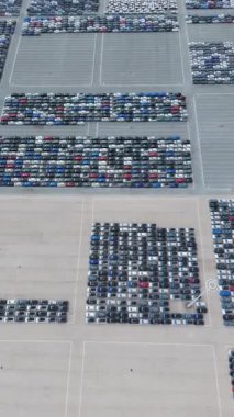 Port 'taki Büyük Boş Otoparktaki Yeni Arabalar Dağıtıma Hazır. Otomotiv endüstrisi. Setubal, Portekiz. Hava Yüksek Açı Drone Atışı. Geriye doğru, yukarı doğru. Dikey Video