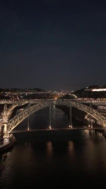 Porto Şehri 'ni, Douro Nehri' ni ve Dom Luis Köprüsü 'nü gece tramvayıyla aydınlattı. Portekiz. Hava Aracı Atışı. İlerleme kaydediyoruz. Dikey Video
