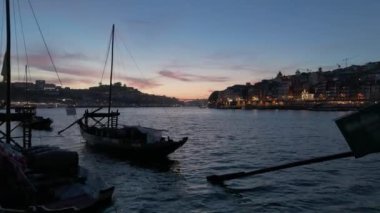 Akşam Alacakaranlığı 'nda Douro Nehri' nde Porto Şehri ve Port Şarap Fıçılarıyla Aydınlanmış Tekneler. Porto, Vila Nova de Gaia, Portekiz. Hava Aracı Atışı. Yavaşça İleri ve Yukarı Gidiyor