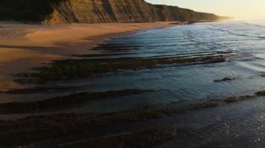 Low Tide sırasında Sunset 'teki Magoito Sahili ve Kayalıkları. Atlantik Okyanusu, Portekiz. Altın Saat. Hava görüntüsü. Kayaların Üzerinde İlerliyor, Eğiliyor