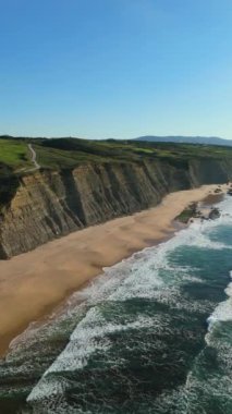 Güneşli bir günde Magoito Sahili ve Kayalıkları. Atlantik Okyanusu, Portekiz. Hava görüntüsü. İleriye ve yukarıya doğru ilerliyoruz. Dikey Video