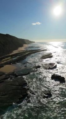 Güneşli bir günde Magoito Sahili ve Kayalıkları. Atlantik Okyanusu, Portekiz. Hava görüntüsü. Geri çekiliyorum. Dikey Video