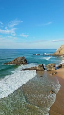 Güneşli bir günde Adraga Sahili ve Kayalıklar. Atlantik Okyanusu, Portekiz. Hava görüntüsü. İleri, aşağı doğru hareket edin. Dikey Video