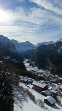 Güneşli kış gününde Lauterbrunnen Vadisi ve Karlı Dağlar. İsviçre Alpleri. İsviçre. Hava görüntüsü. İleriye ve yukarıya doğru ilerliyoruz. Wengen 'dan görüntü. Dikey Video
